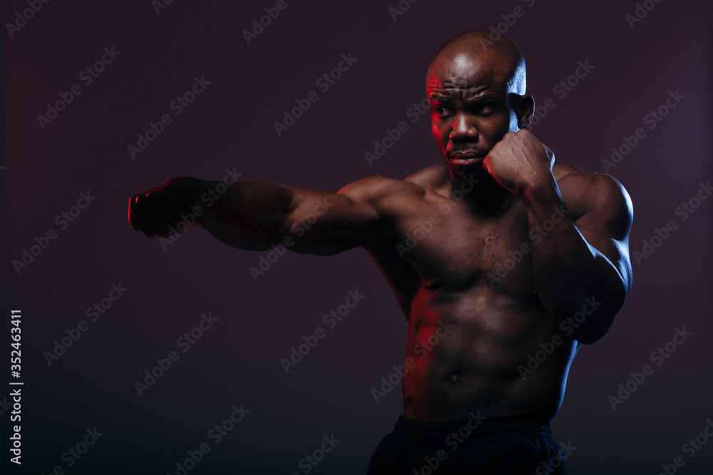 Professional black boxer boxing and doing exercises before a neon light wrestling competition