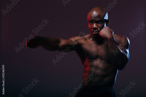 Professional black boxer boxing and doing exercises before a neon light wrestling competition © DmitryStock