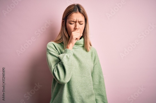 Young beautiful blonde woman wearing winter wool sweater over pink isolated background feeling unwell and coughing as symptom for cold or bronchitis. Health care concept. © Krakenimages.com