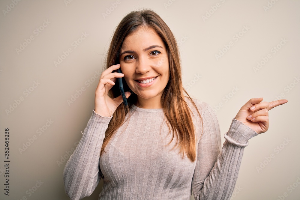 Young woman having a conversation speaking on smartphone over isolated background very happy pointing with hand and finger to the side Young woman having a conversation speaking on smartphone over isolated background very happy pointing with hand and finger to the side