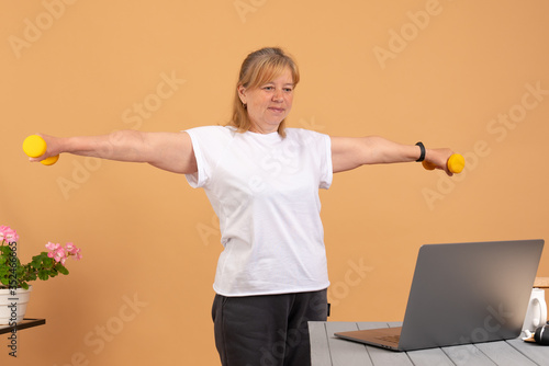 Fit woman doing home workout. Laptop computer with online gym training course. Happy fitness senior female watching exercise video. Personal trainer on the internet. Healthy diet program