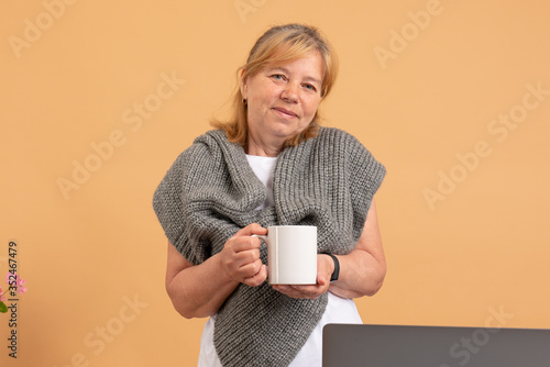 Calm seniorr woman in grey scarf with cup of tee looking at the camera photo