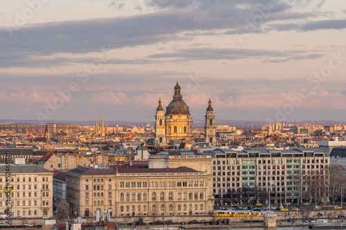 Danube river side view of St. Stephen's Basilica during golden sunset hour with yellow tram carriage © Davidzfr