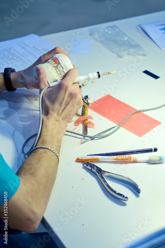 The dentist works with tools on the impression of teeth creating implants photo