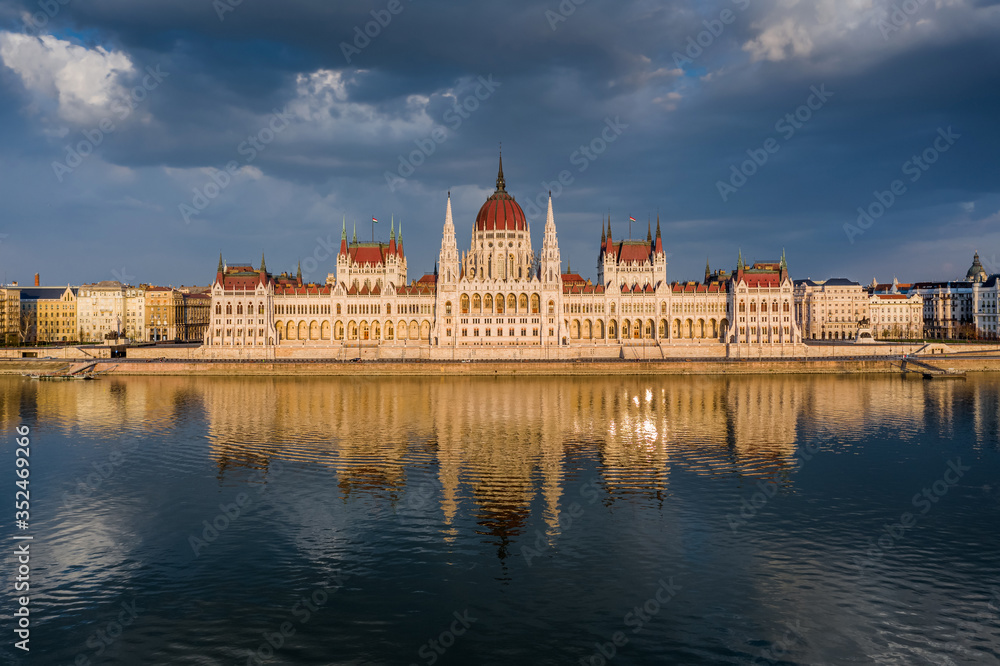 Obraz premium Budapest, Hungary - Aerial view of the beautiful Hungarian Parliament building with reflection and warm golden sunlight at sunset. The streets are totally empty due to the 2020 Coronavirus pandemic