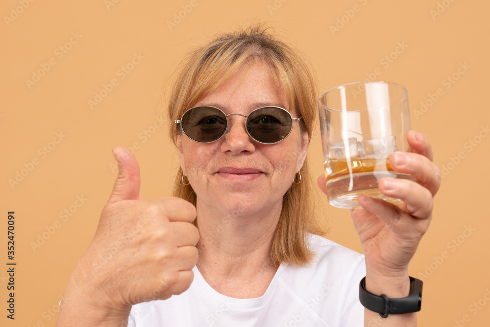 Concept woman in black sunglasses with alcohol problems with whiskey in a glass Concept woman in black sunglasses with alcohol problems with whiskey in a glass