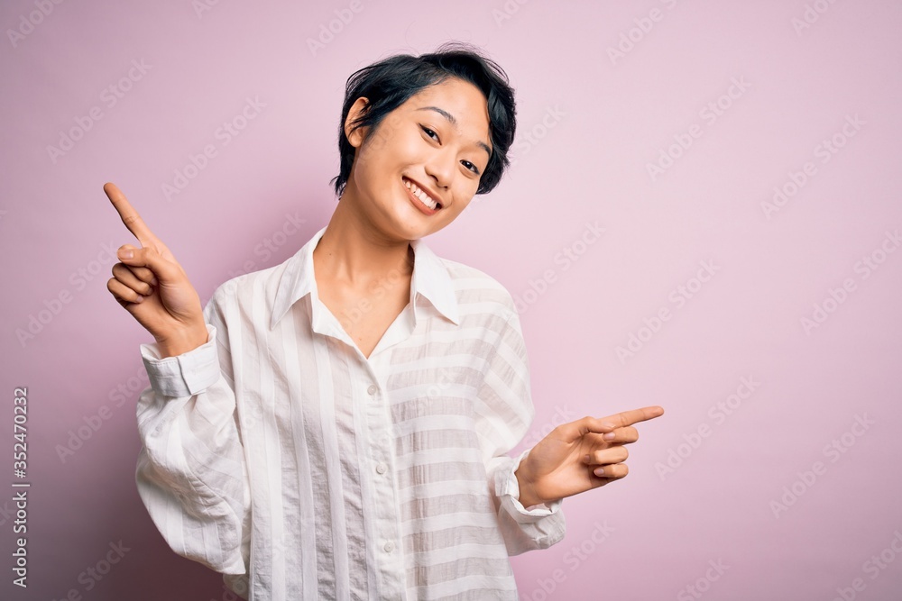 Young beautiful asian girl wearing casual shirt standing over isolated pink background smiling confident pointing with fingers to different directions. Copy space for advertisement Young beautiful asian girl wearing casual shirt standing over isolated pink background smiling confident pointing with fingers to different directions. Copy space for advertisement