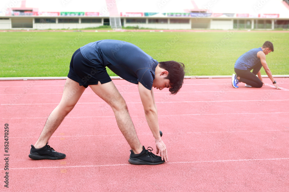 Young runner men stretching body before exercise run outdoor on athletic track, jogger athlete training workout outdoor, sport man doing exercise at track and field stadium