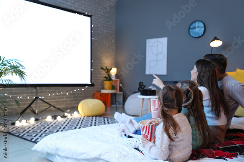 Canvas-taulu Young family watching movie at home