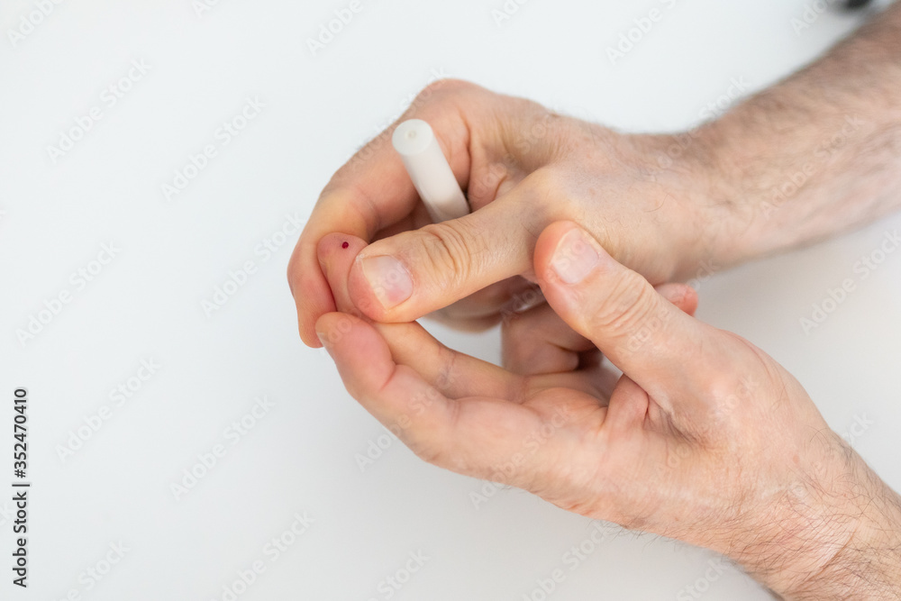 Unidentified person measures blood sugar, pricking his middle finger Unidentified person measures blood sugar, pricking his middle finger