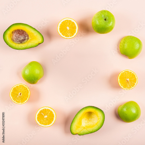 Ripe fruit orange, lemon, apple and avocado on a pink background.