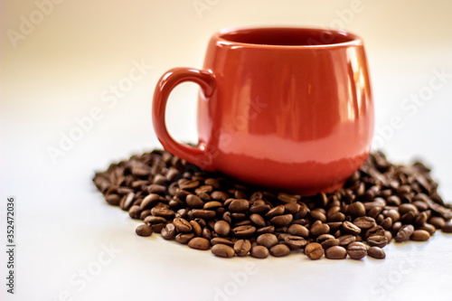 Pink coffee cup and beans on a white background. Side view of pink cup of coffee with beans on white table. Space for text. Close up.