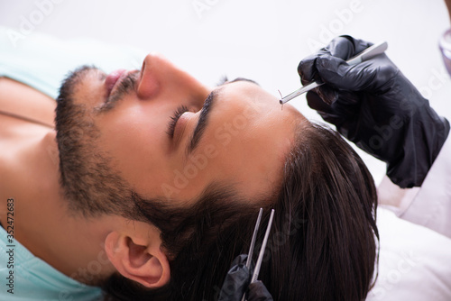 Young man visiting female beautician in hair transplantation con