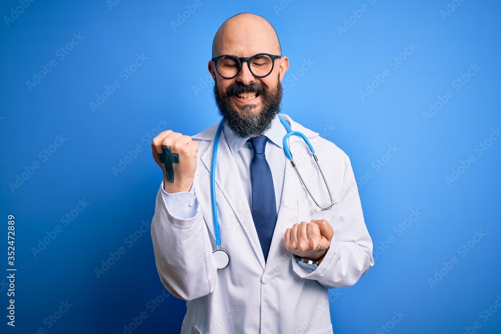 Handsome bald doctor man with beard wearing glasses and stethoscope over blue background celebrating surprised and amazed for success with arms raised and eyes closed. Winner concept. Handsome bald doctor man with beard wearing glasses and stethoscope over blue background celebrating surprised and amazed for success with arms raised and eyes closed. Winner concept.