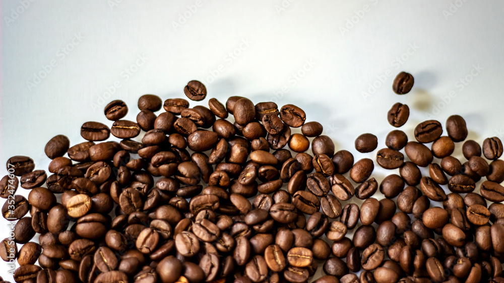 Falling roasted coffee beans isolated on white background.Close up of coffee beans.Beans isolated on white background top view.Grains of coffee. Brown coffee beans isolated on white board.Copy-space