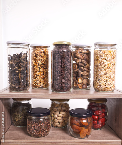 Bulk foods storage in glass jars: dry wild mushrooms, muesli, chocolate, nuts, dates, pistachio, aromatic herbs