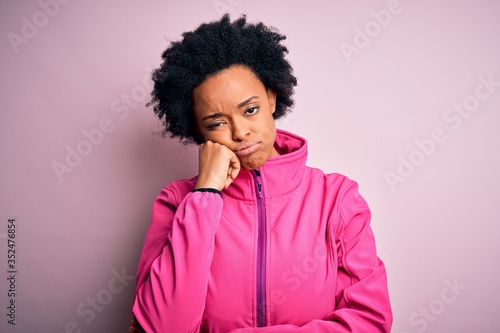 Young African American afro sportswoman with curly hair wearing sportswear doin sport thinking looking tired and bored with depression problems with crossed arms.