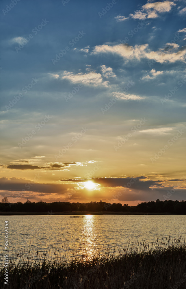 Vertical panoramic photo of beautiful blue sunset sky with a yellow sun that shines through the clouds
