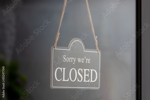 sorry we are closed sign hang on claer glass door of shop. photo