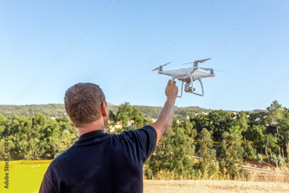 Young man, an engineer pilot, a drone, prepares quadrocopter for take-off, for testing and filming a vileo and photograph. By controlling the remote. Young man, an engineer pilot, a drone, prepares quadrocopter for take-off, for testing and filming a vileo and photograph. By controlling the remote.