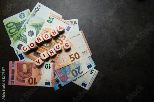 euro banknotes on a dark background with coronavirus inscription view from top