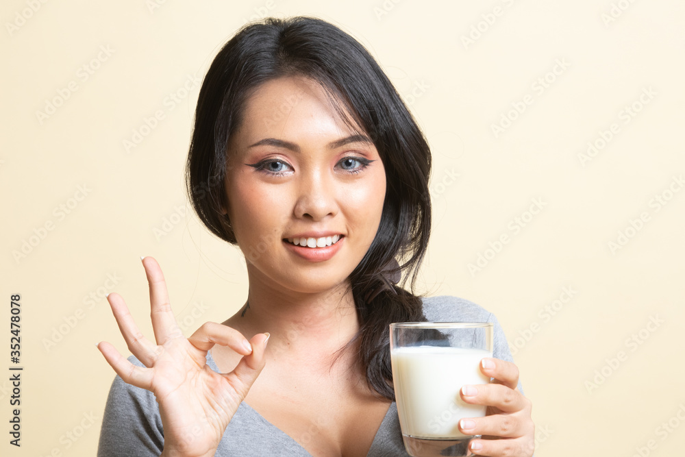 Healthy Asian woman drinking a glass of milk show OK sign. Healthy Asian woman drinking a glass of milk show OK sign.