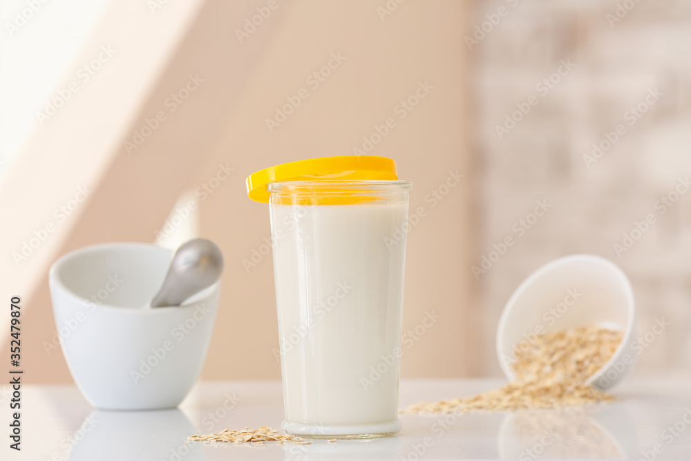 Glass of tasty oat milk on table