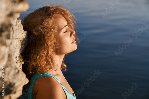 Cuadro en lienzo Girl with closed eyes meditating near rock and water.