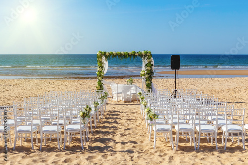 Romantic view and flower decorations on the beach near the sea  for a wedding ceremony with flowers. Europe  Portugal  against backdrop of bright sun.