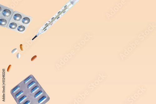Pills for levitation. Pills and thermometer on a blue background that fall down. Pills, medicine and health. Virus protection concept. Flat lay, top view, copy space