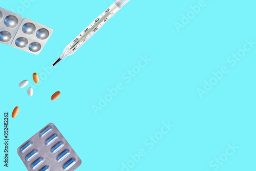 Pills for levitation. Pills and thermometer on a blue background that fall down. Pills, medicine and health. Virus protection concept. Flat lay, top view, copy space
