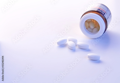 White pill out from glass jar on white background. Virus protection concept. Copy space. 
