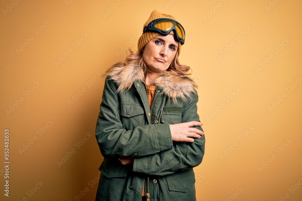 Middle age beautiful blonde skier woman wearing snow sportwear and ski goggles shaking and freezing for winter cold with sad and shock expression on face Middle age beautiful blonde skier woman wearing snow sportwear and ski goggles shaking and freezing for winter cold with sad and shock expression on face