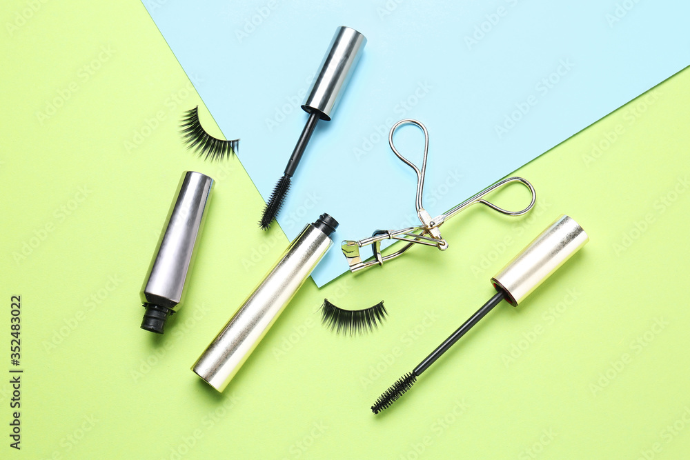 Mascara with fake eyelashes and curler on color background Mascara with fake eyelashes and curler on color background