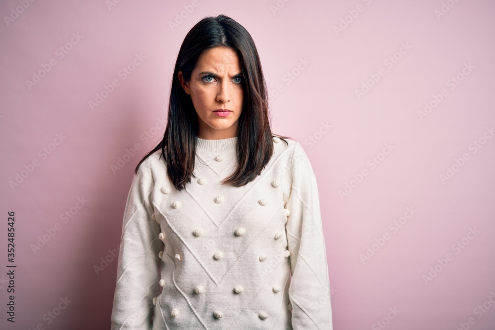 Fototapeta premium Young brunette woman with blue eyes wearing casual sweater over isolated pink background skeptic and nervous, frowning upset because of problem. Negative person.