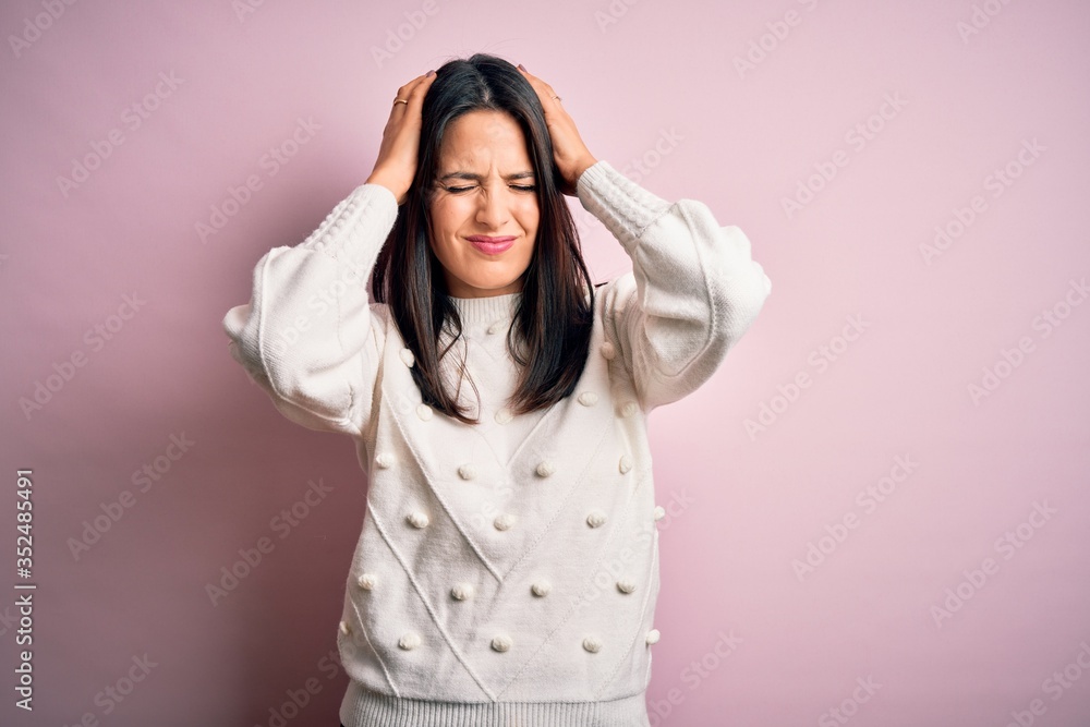 Young brunette woman with blue eyes wearing casual sweater over isolated pink background suffering from headache desperate and stressed because pain and migraine. Hands on head. Young brunette woman with blue eyes wearing casual sweater over isolated pink background suffering from headache desperate and stressed because pain and migraine. Hands on head.