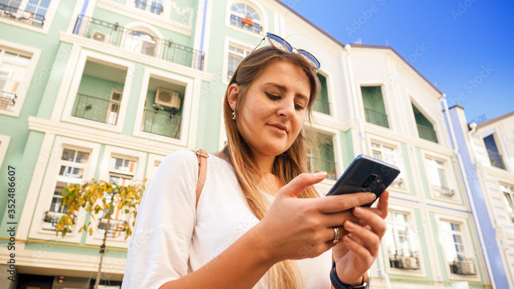 Portrait of beautiful smiling girl on city street using smartphone Portrait of beautiful smiling girl on city street using smartphone