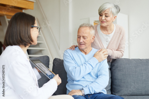 Portrait of modern senior couple listening to female doctor and looking at lung x-ray image during consultation in clinic