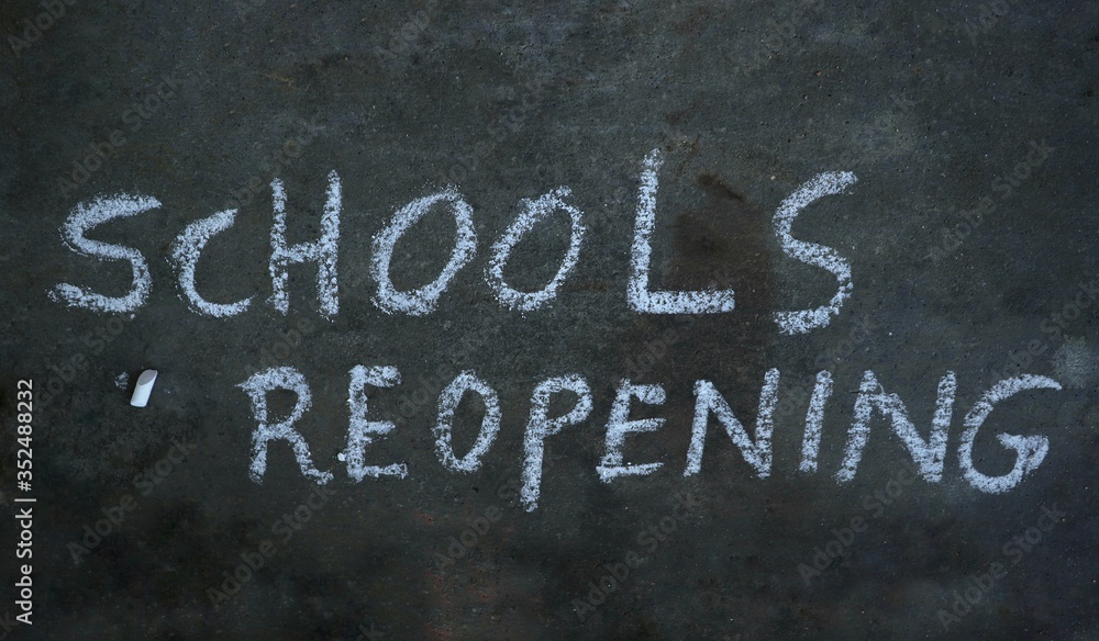 Fototapeta premium Schools Reopening Written with White Chalk on Black Surface