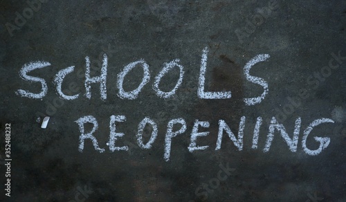 Schools Reopening Written with White Chalk on Black Surface