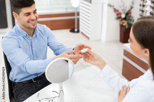 фотографія Happy man visiting ophthalmologist and choosing eye lenses
