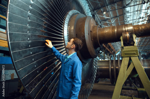 Engineer checks turbine impeller vanes, factory photo
