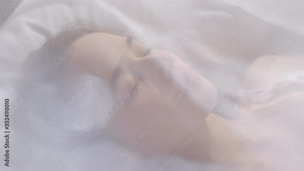 Slowmo high angle shot of beautiful young woman sleeping in bed under sheer canopy, then waking up and smiling Slowmo high angle shot of beautiful young woman sleeping in bed under sheer canopy, then waking up and smiling