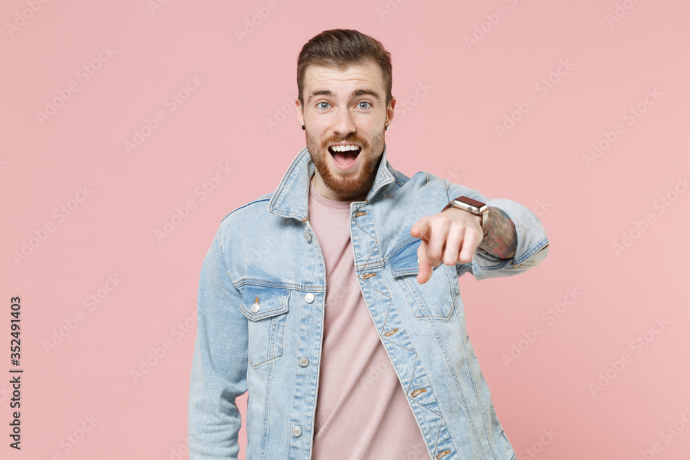 Excited young bearded man guy in denim casual jacket posing isolated on pastel pink background studio portrait. People emotions lifestyle concept. Mock up copy space. Pointing index finger on camera. Excited young bearded man guy in denim casual jacket posing isolated on pastel pink background studio portrait. People emotions lifestyle concept. Mock up copy space. Pointing index finger on camera.