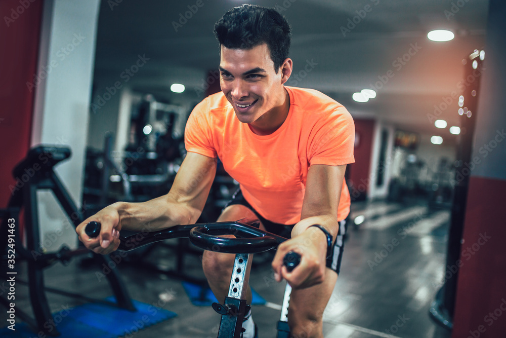 Man biking in the gym, exercising legs doing cardio workout cycling bikes. Man biking in the gym, exercising legs doing cardio workout cycling bikes.