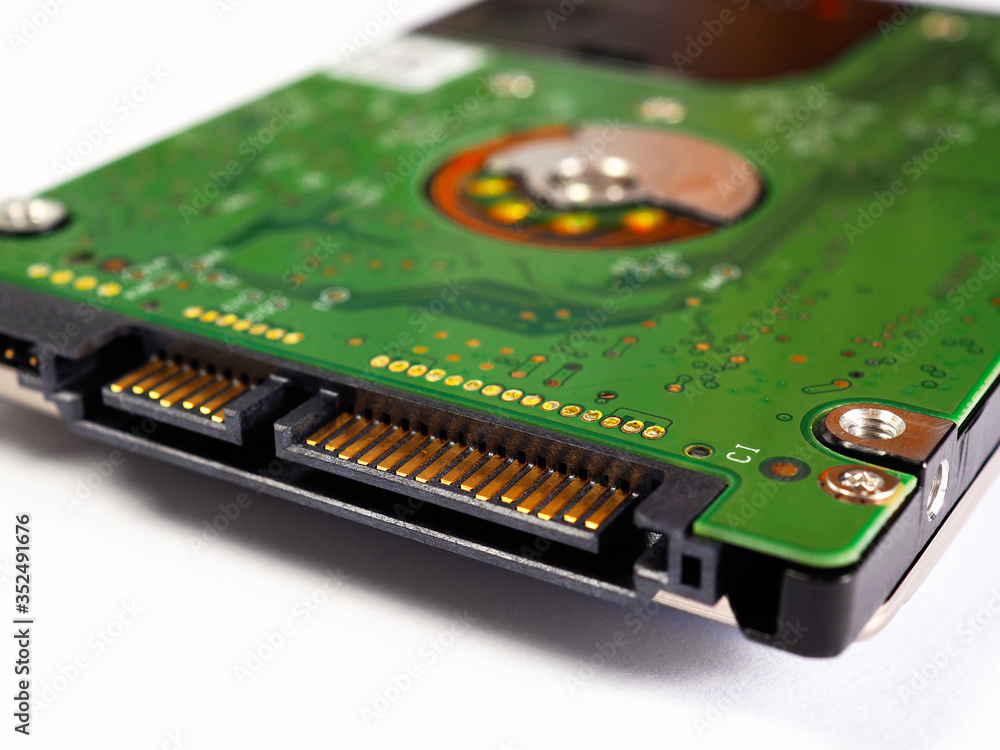 Hard drive HDD of a computer or laptop. Fragment close-up. Green circuit board PCB lies on a white paper background. IT&C. Illustration: computer hardware and equipment. Not isolated. Macro Hard drive HDD of a computer or laptop. Fragment close-up. Green circuit board PCB lies on a white paper background. IT&C. Illustration: computer hardware and equipment. Not isolated. Macro