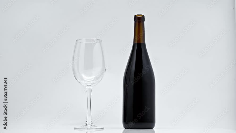 black bottle and glass spinning around on grey black bottle and glass spinning around on grey