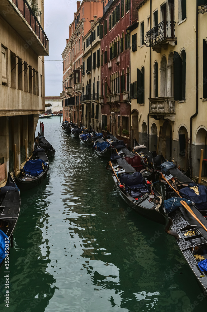 Venetian canal with boats and old facades of houses.