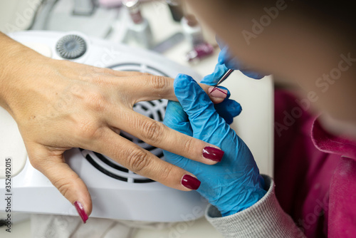 Concept: personal care, manicure. Manicurist working. Girl doing nail work on adult woman hands. Hands detail. Working on acrylic nail paint.