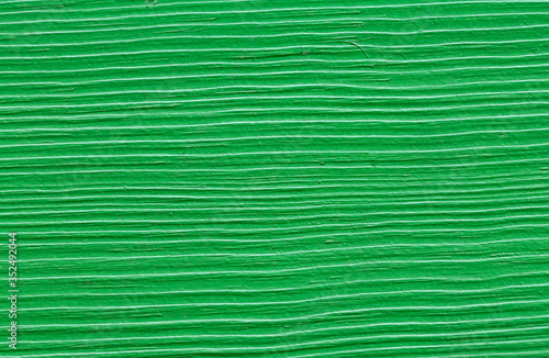 A fragment of old paint on a wooden board. Stripes, green color